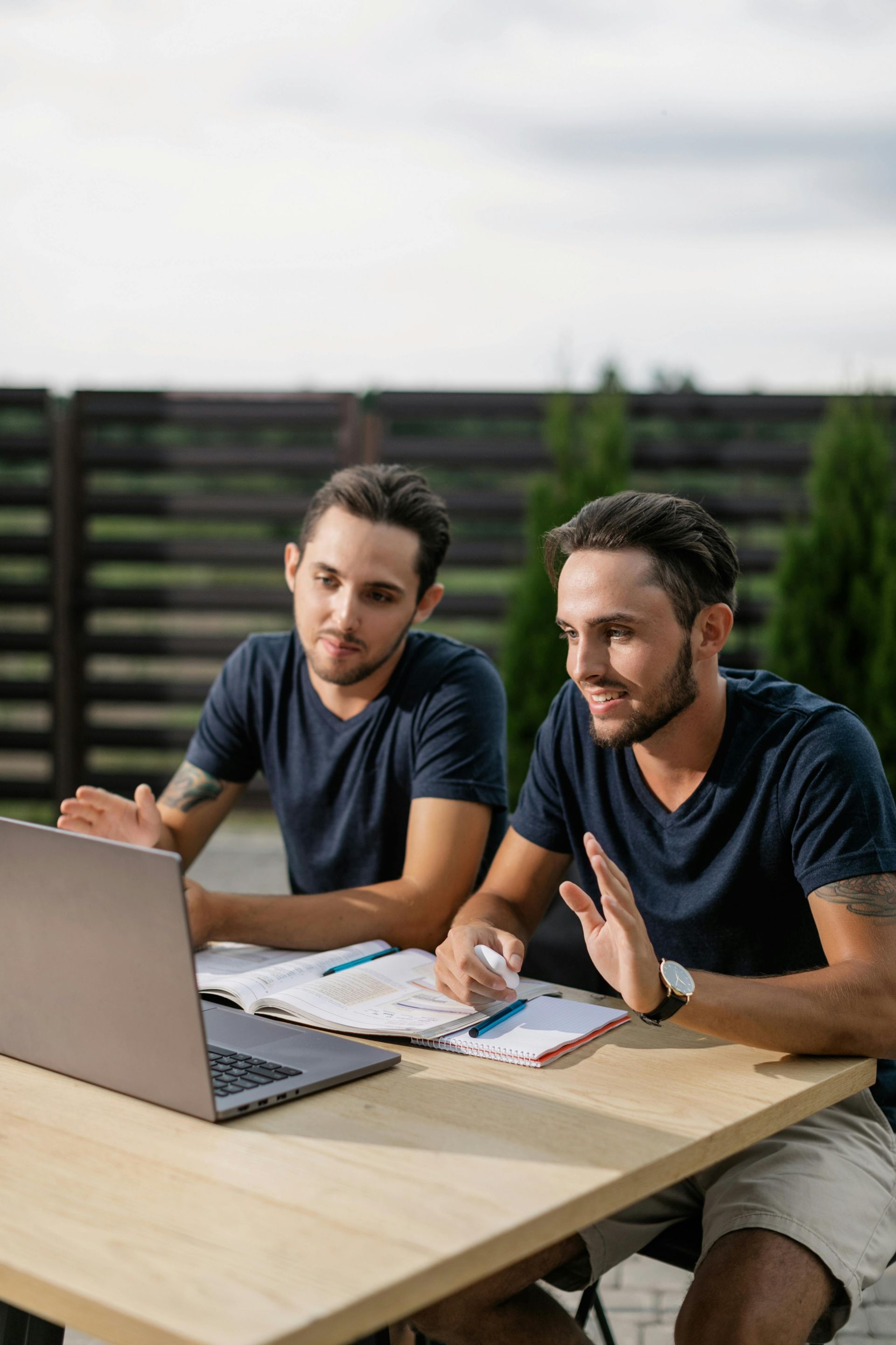 Two men are sitting at a table looking at a laptop.