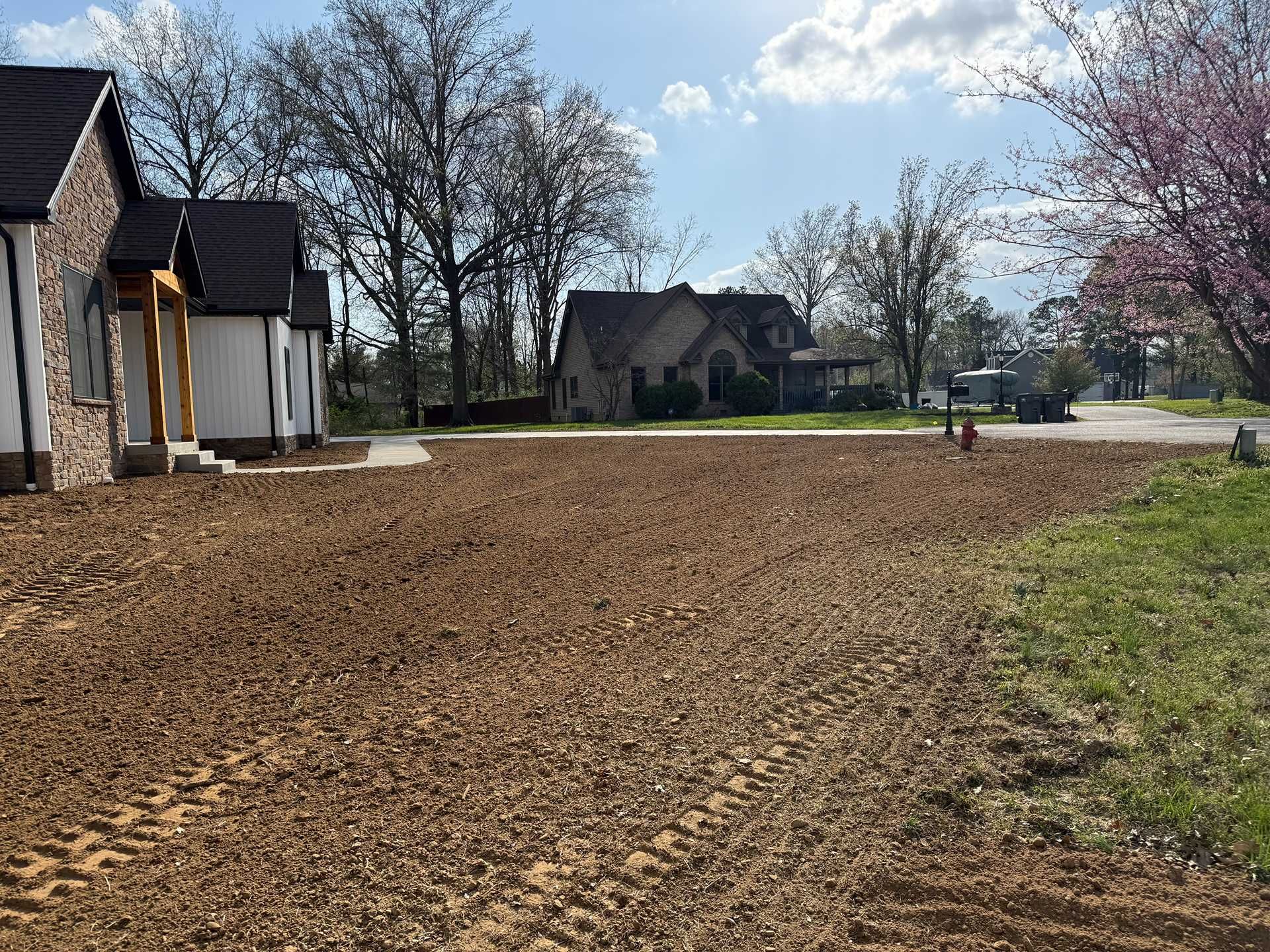 New homes beside a freshly graded dirt lot under a clear sky