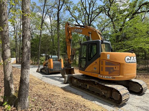 Yellow excavator on a gravel road in a wooded forest clearing