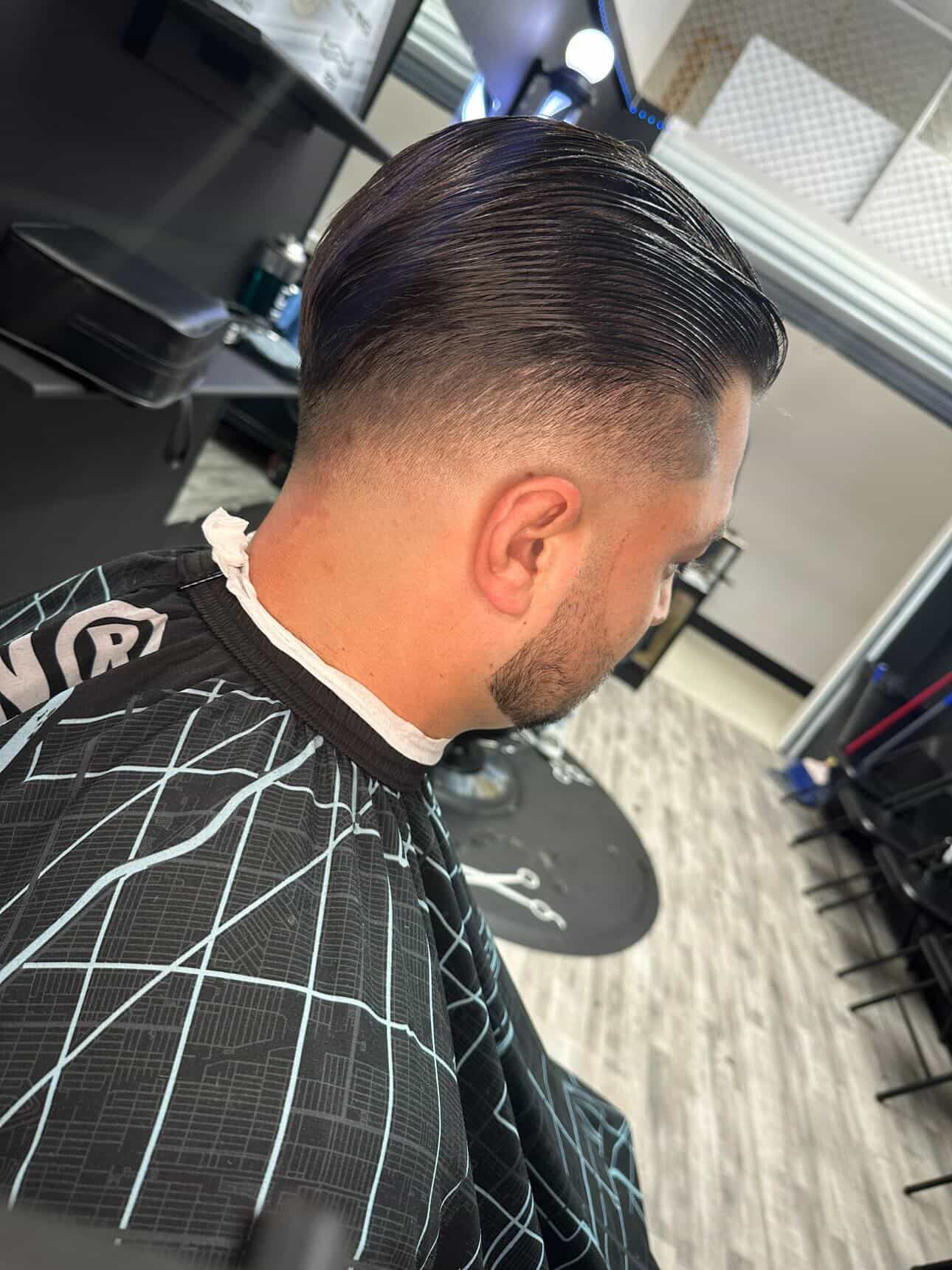Hairdresser trimming a man's beard with scissors in a salon, close-up view.