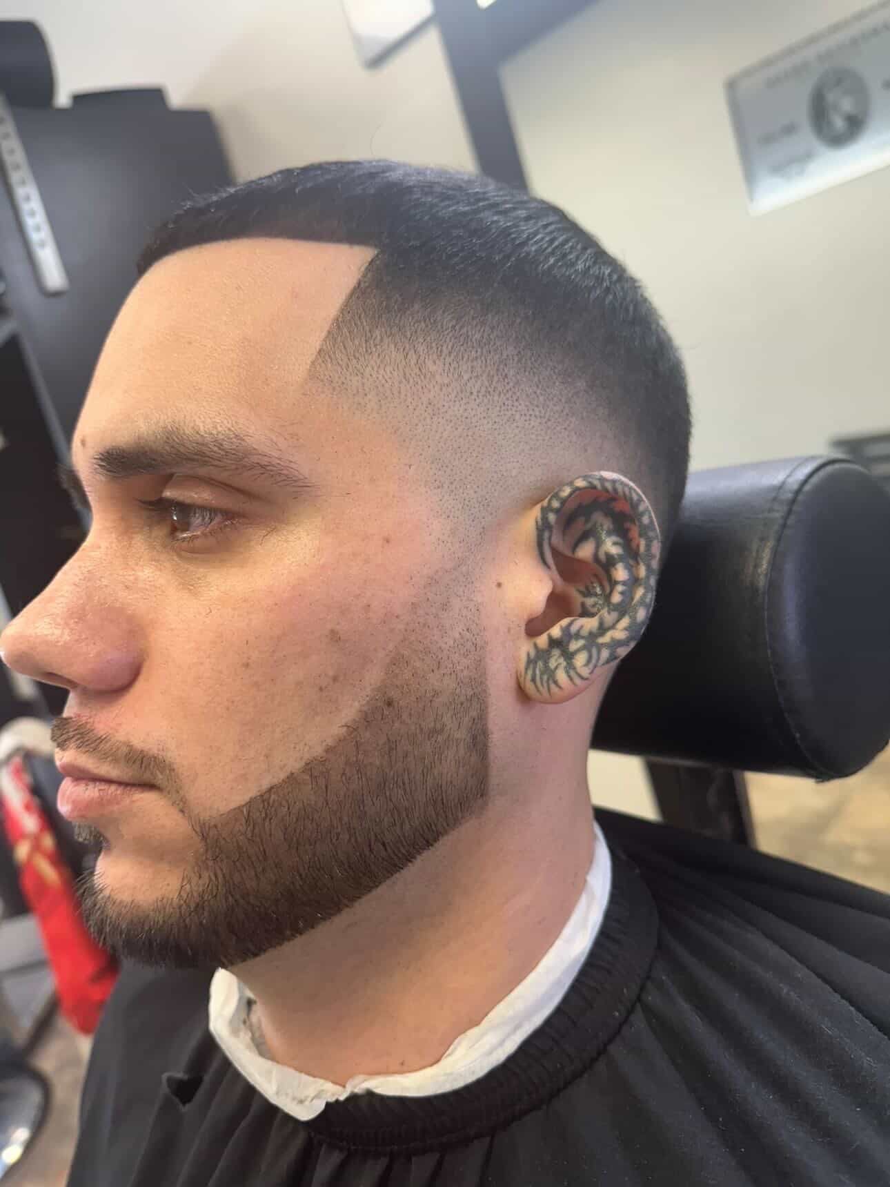 Man in a barber chair receiving a straight-razor shave with shaving cream applied to his cheek.