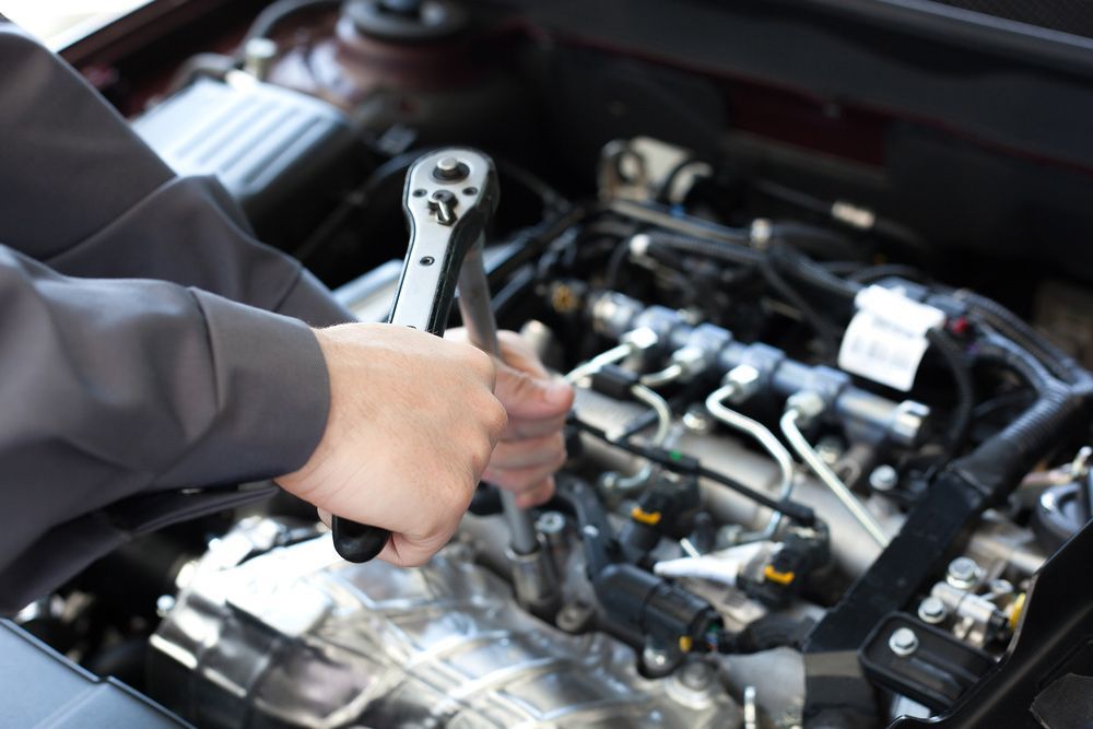 A Person Is Working On A Car Engine With A Wrench — MJ's Mobile Car Mechanic In Thirroul, NSW
