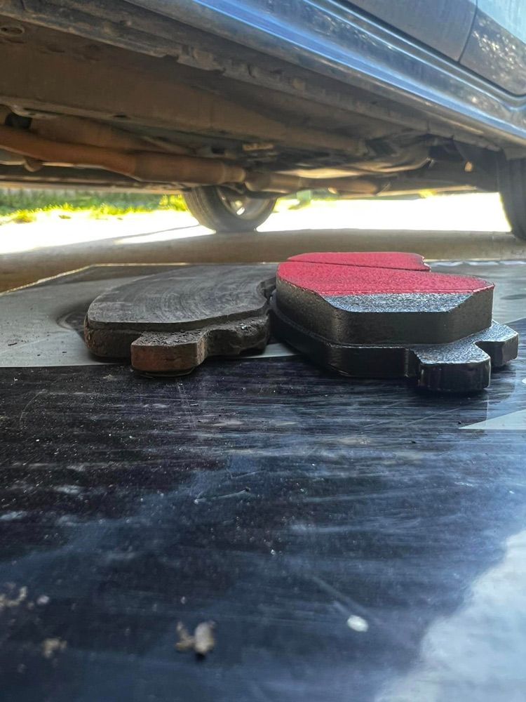 A Pair Of Brake Pads Are Laying On The Ground Under A Car— MJ's Mobile Car Mechanic In Fairy Meadow, NSW