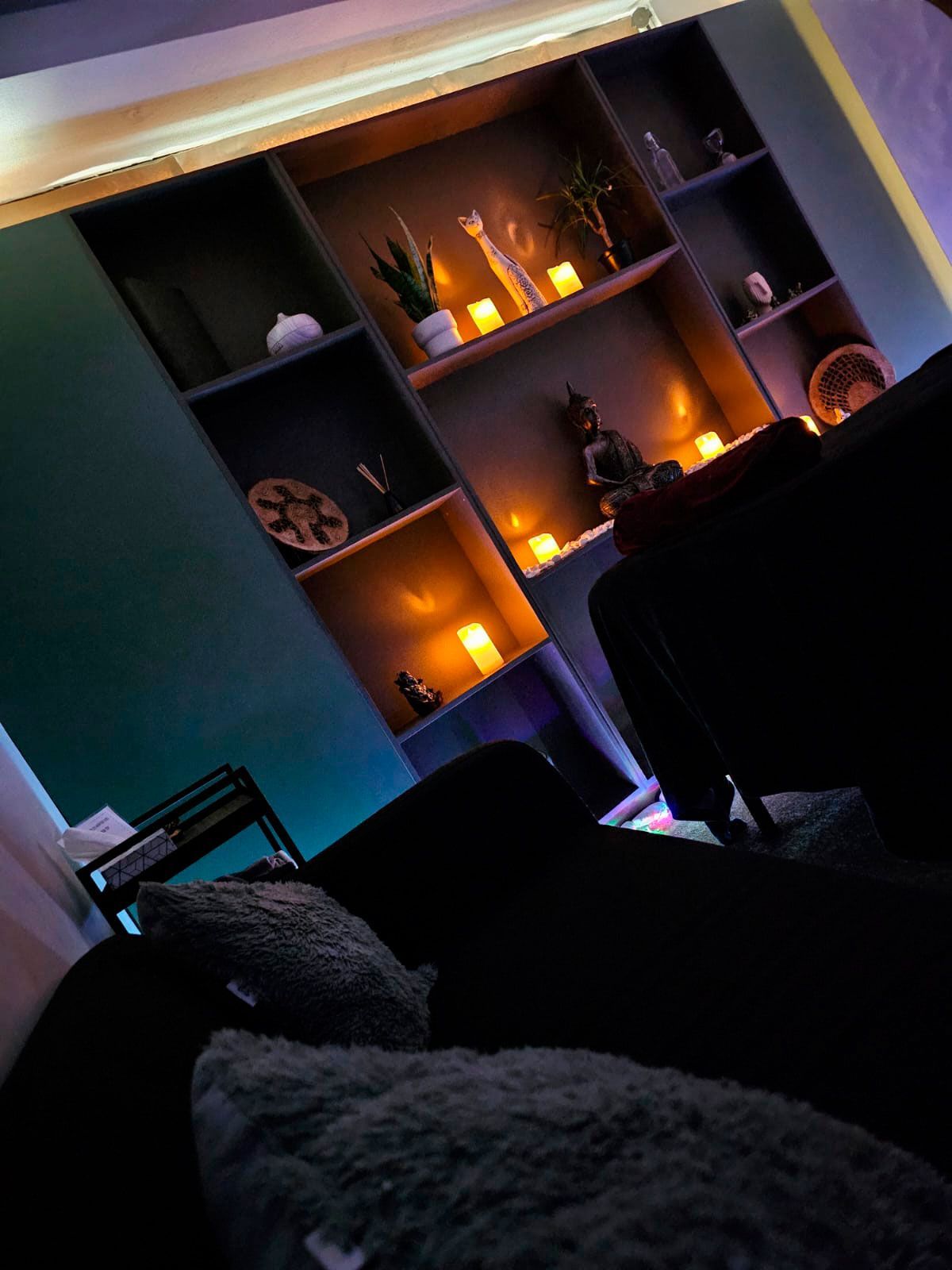 Una sala de estar con un sofá y estantes con velas.