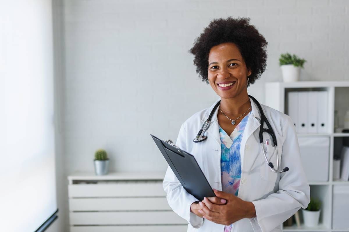 Black female doctor holding clipboard and smiling at MDCredentialing