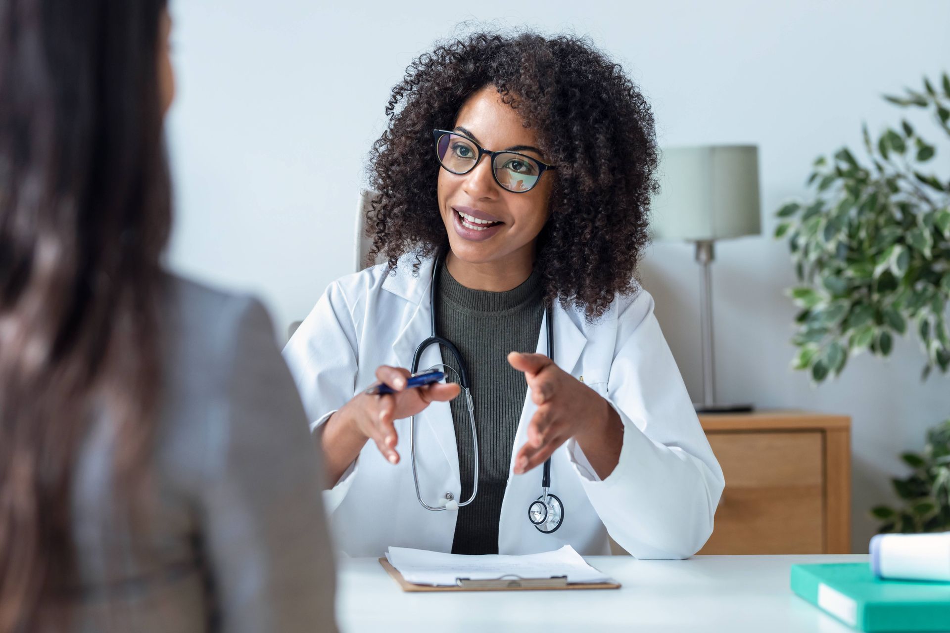 Female physician sitting at a desk talking to a patient.