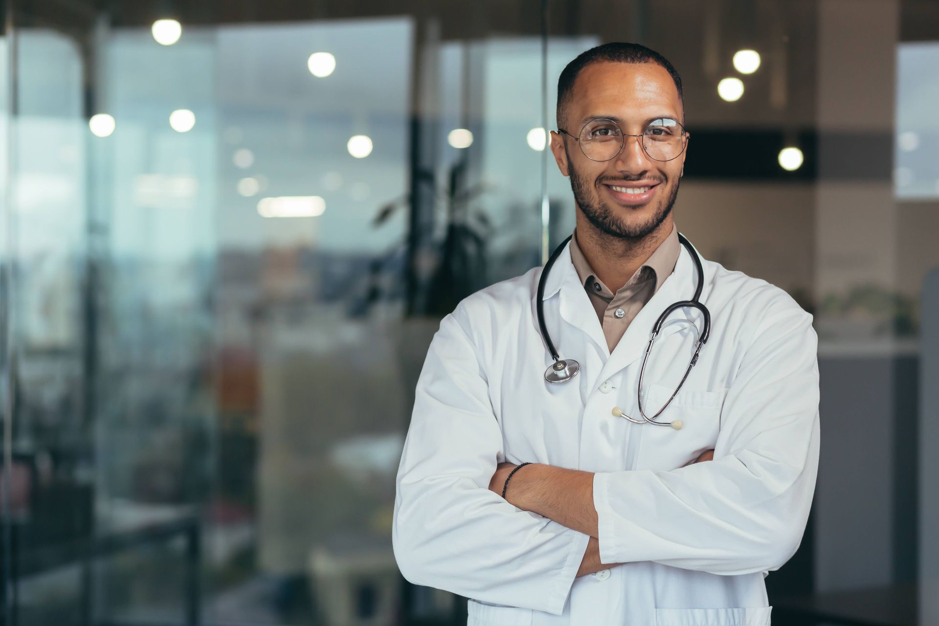 Male physician standing against a wall smiling.