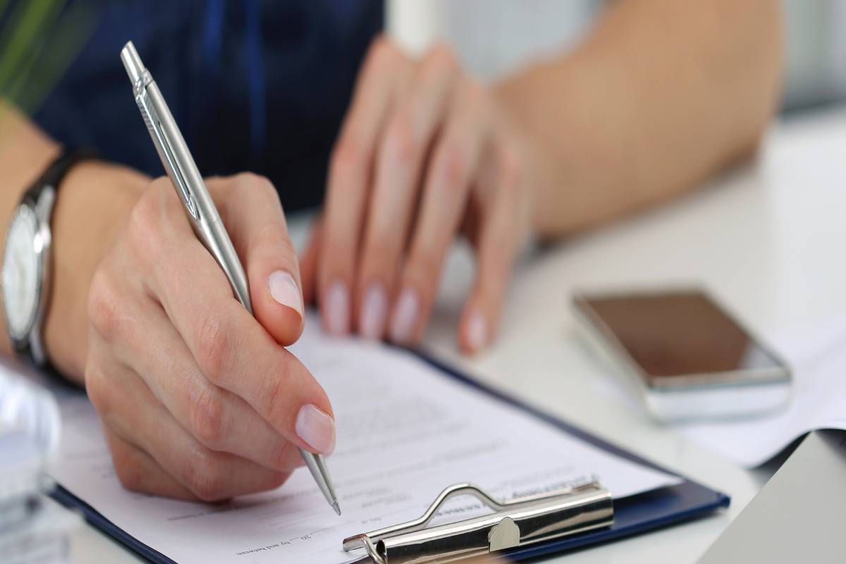 Woman's hands signing a document on clipboard at MDCredentialing