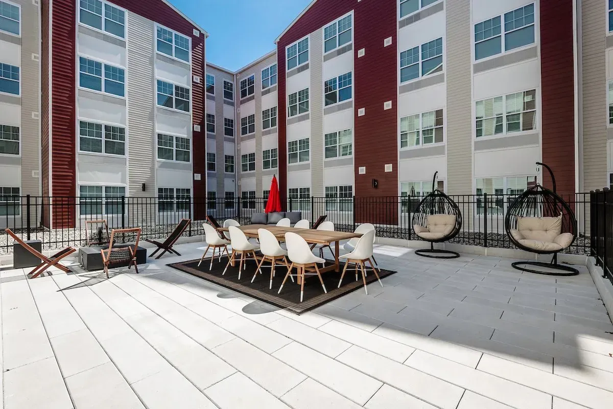 A large building with a patio area with a table and chairs in front of it.