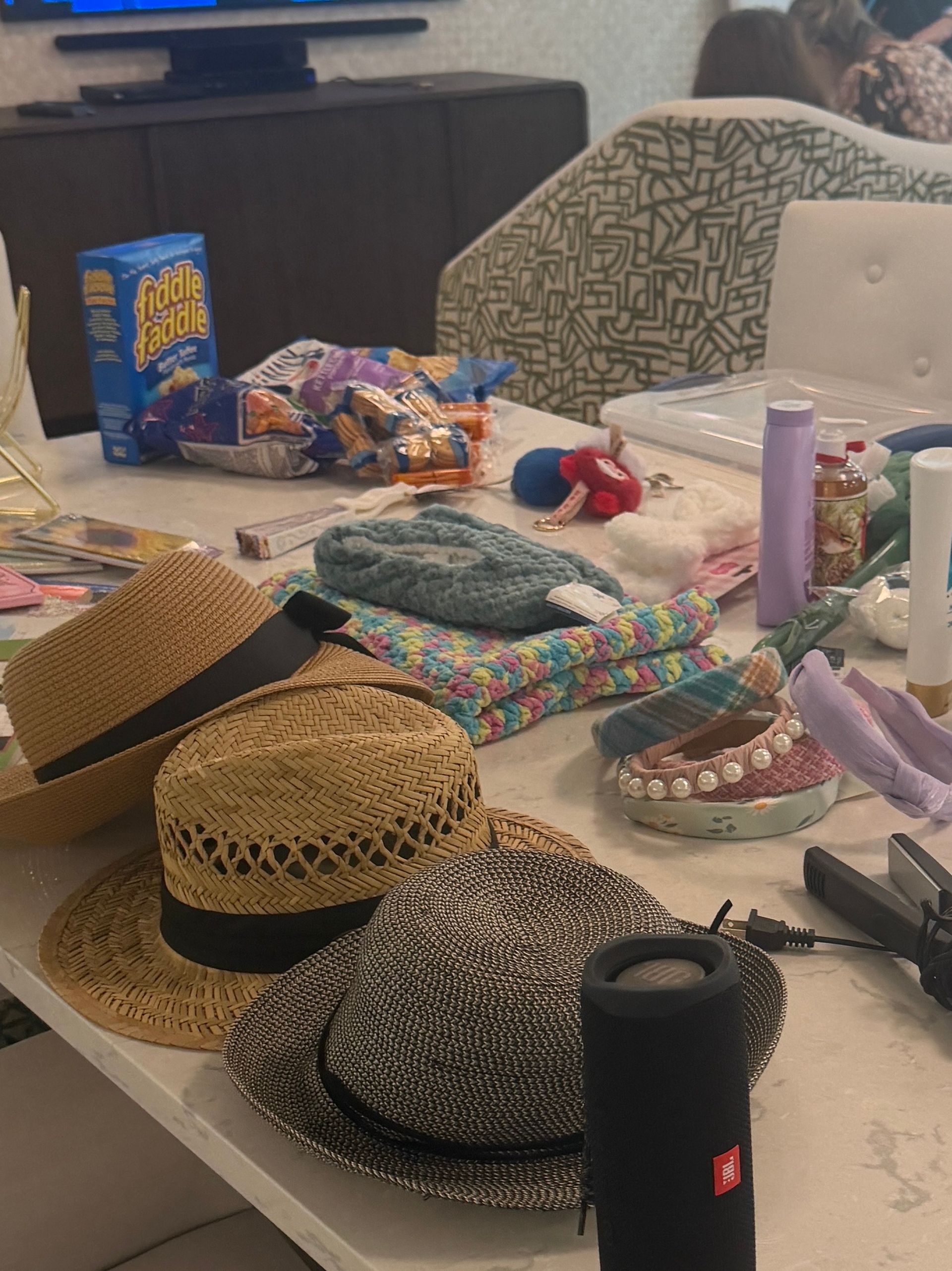 Table covered with assorted hats, snacks, and small items in a casual indoor setting