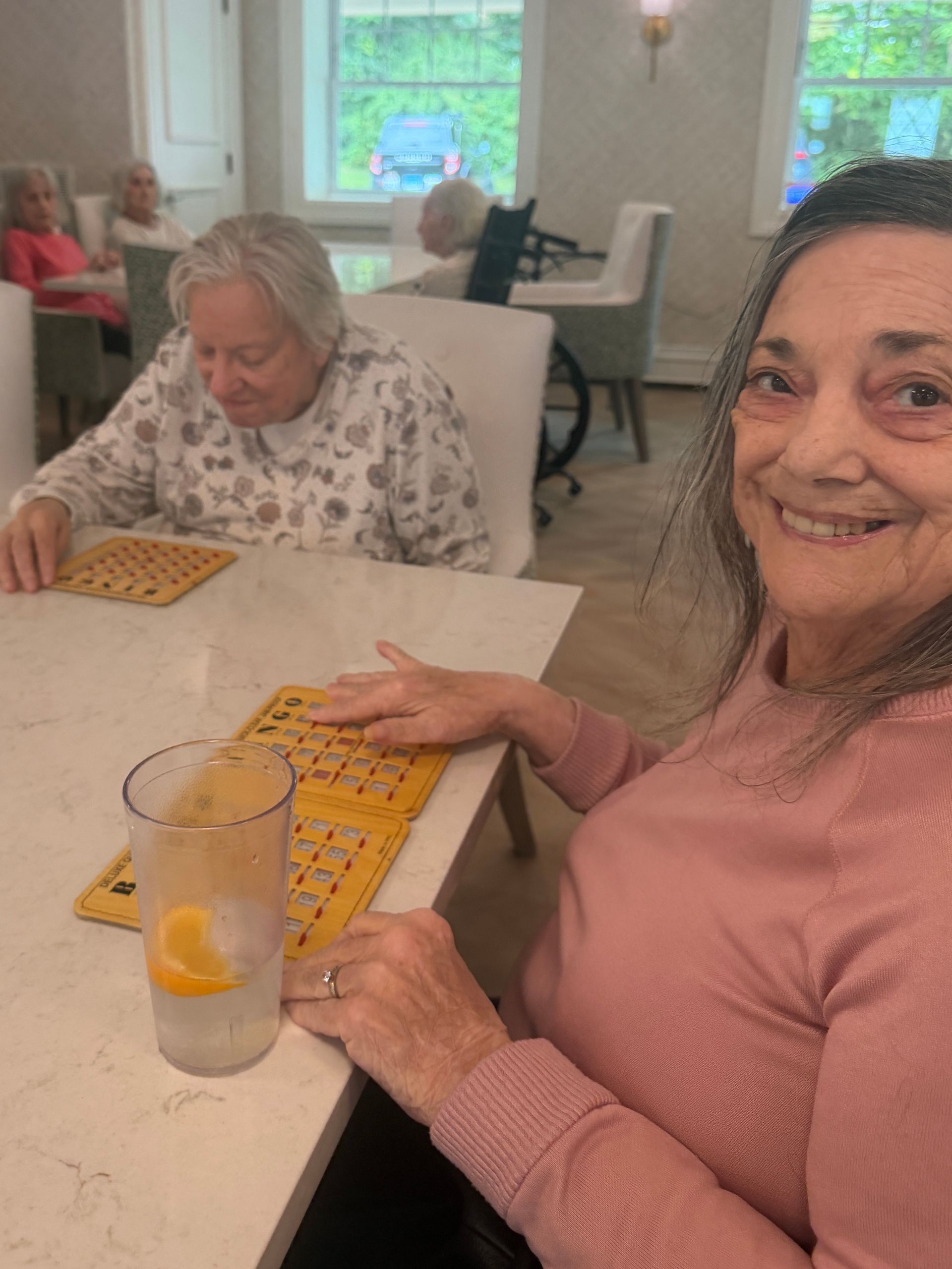 Woman smiling at a table while playing a yellow board game in a bright room
