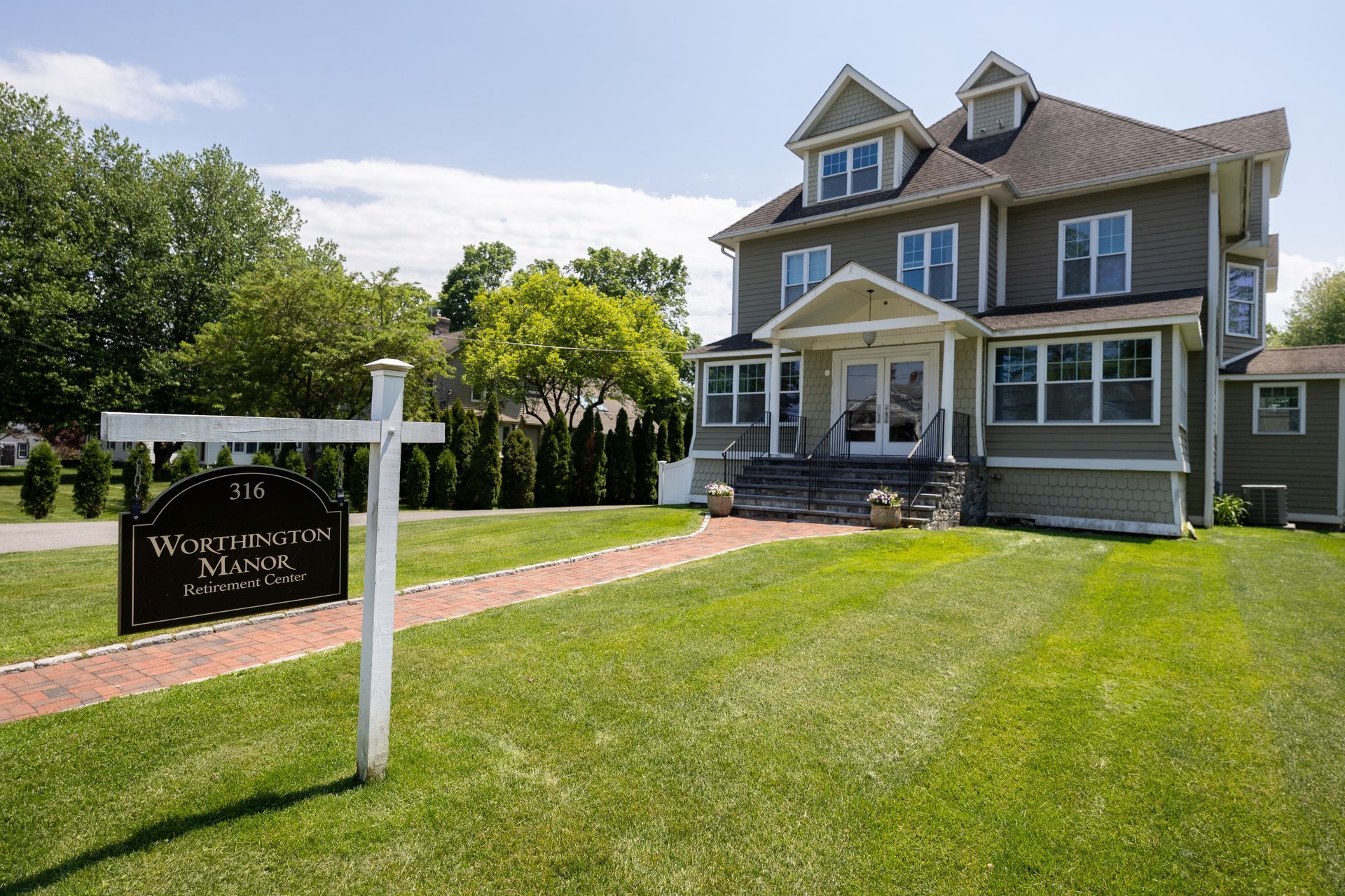 Victorian house with a “For Sale” sign on a sunny green lawn