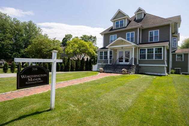 Victorian house with a “For Sale” sign on a sunny green lawn