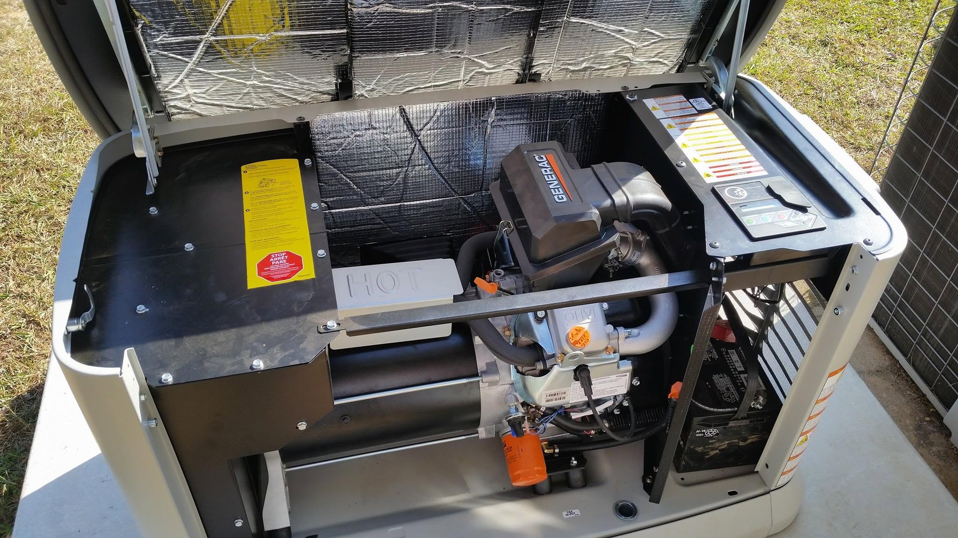 Open generator compartment in a metal enclosure, showing engine, fuel tank, and wiring.