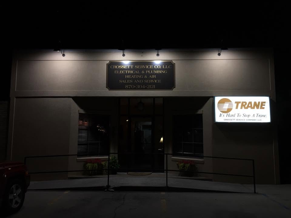 Night exterior of a building entrance with lit signs, including a Trane sign on the right.