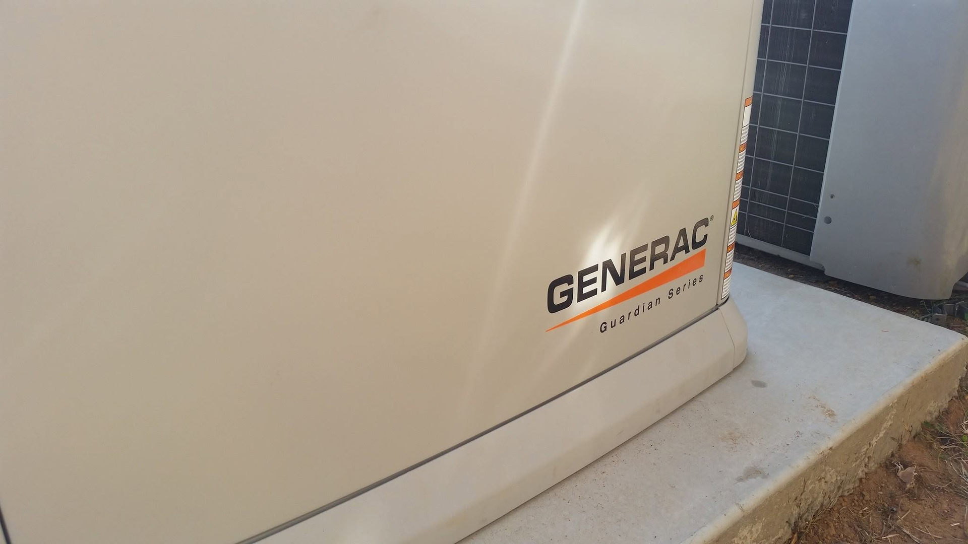 Close-up of a Generac generator unit beside a building wall.
