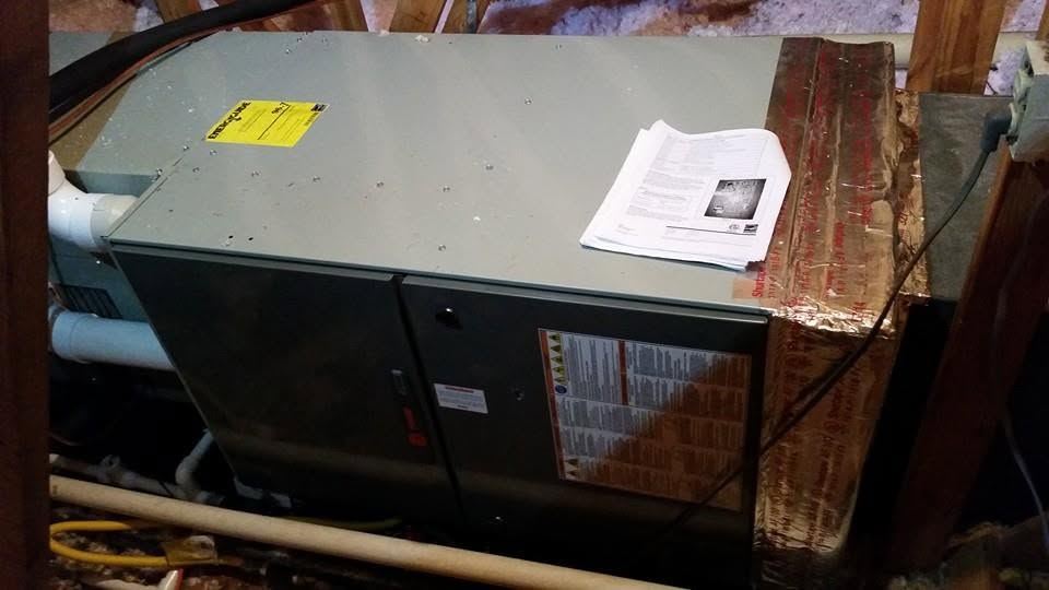 Gray HVAC unit beside wooden stairs with a paper on top and a yellow label