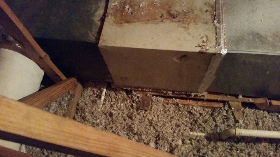 Insulation-filled attic space with exposed beams and ductwork around a central vent box