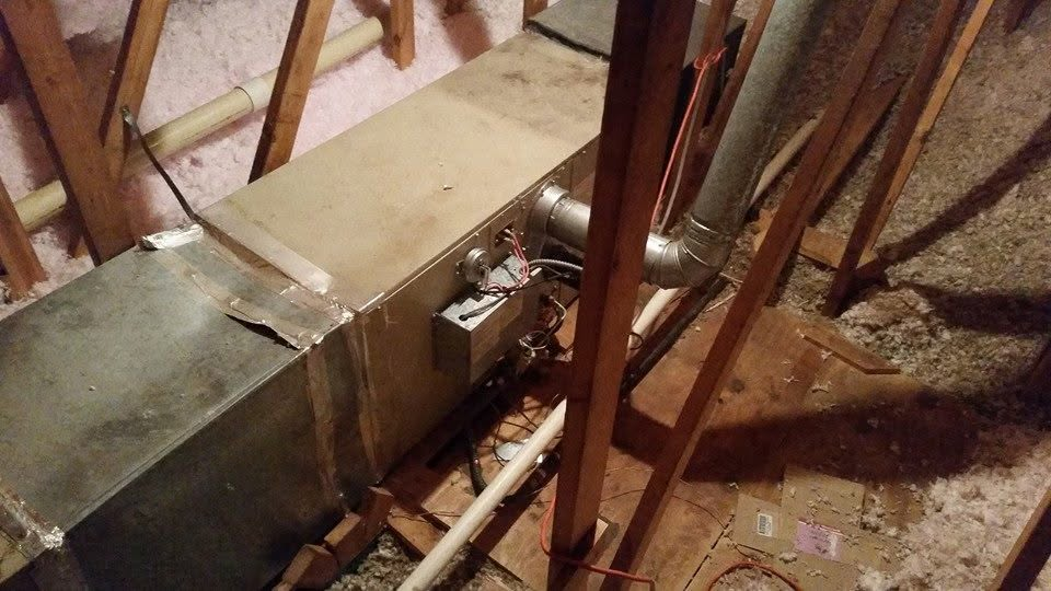 Metal ductwork and a rectangular platform in an unfinished attic, with wooden framing around it.
