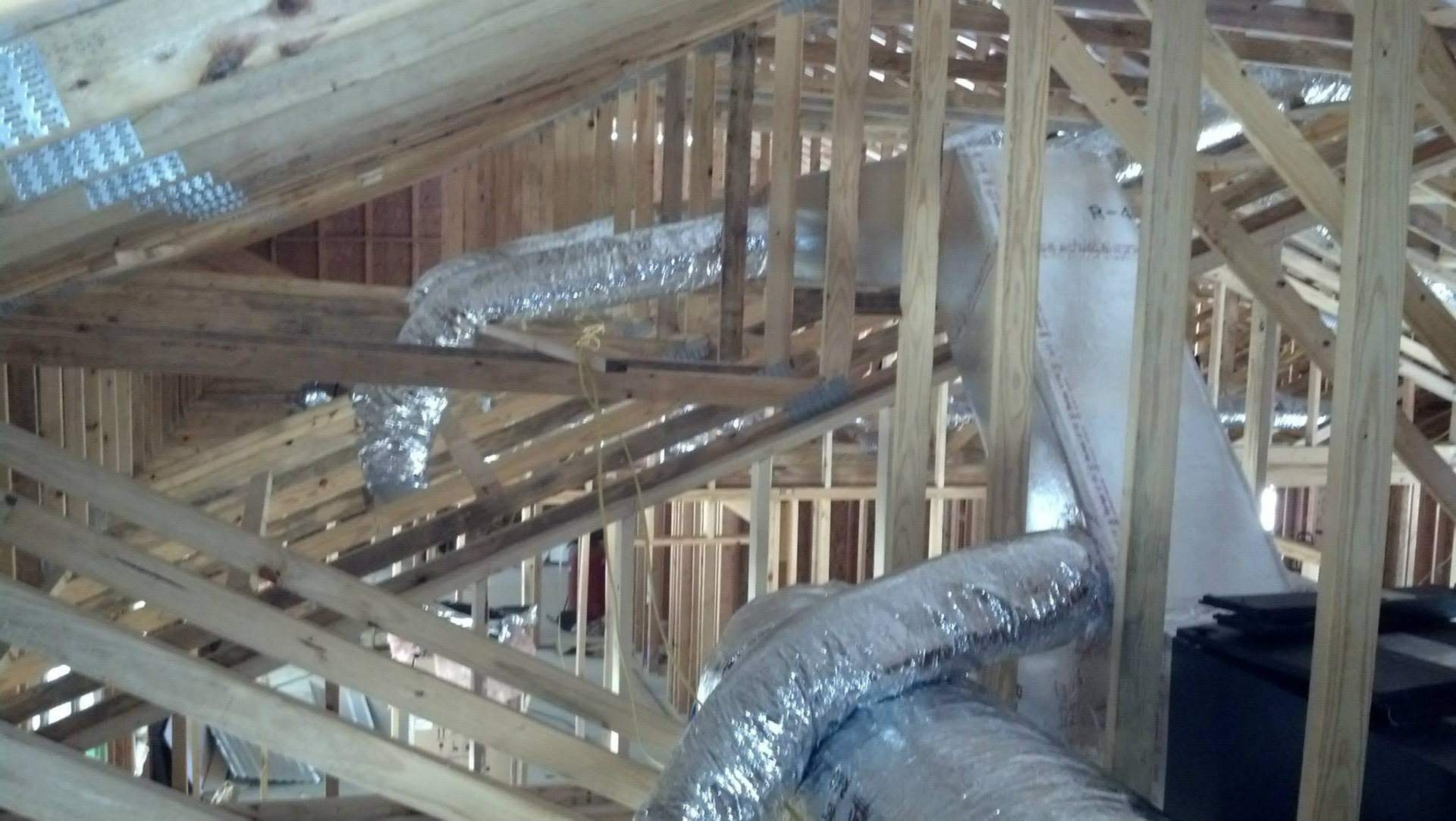 Attic framing with wooden trusses and silver HVAC ducts