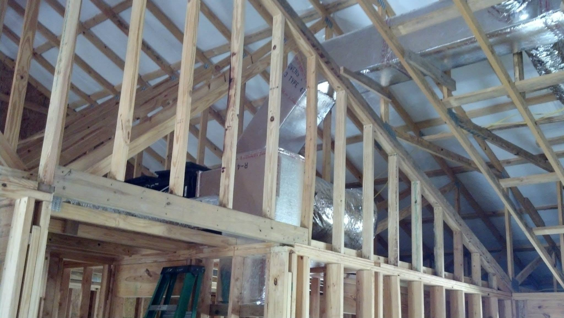 Wooden house framing under construction with exposed studs and roof trusses