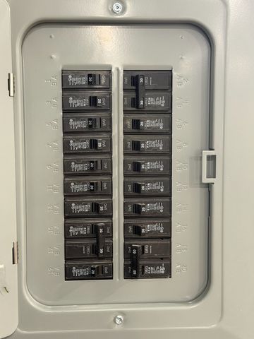 Utility meters and open electrical panels mounted on a brick exterior wall.