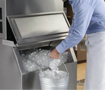 Open stainless-steel ice bin with ice cubes and a rack inside