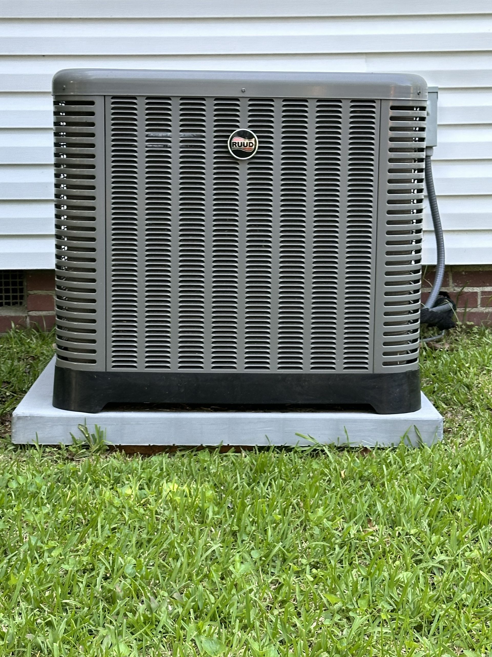 Technician testing an outdoor air conditioner unit with a multimeter and red probe leads