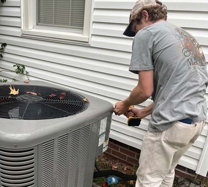 Technician repairing an outdoor air conditioner beside a house