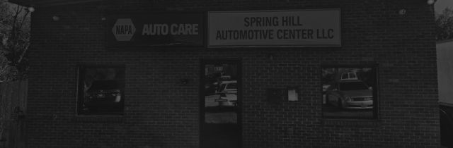 A gray automotive shop with signs that read