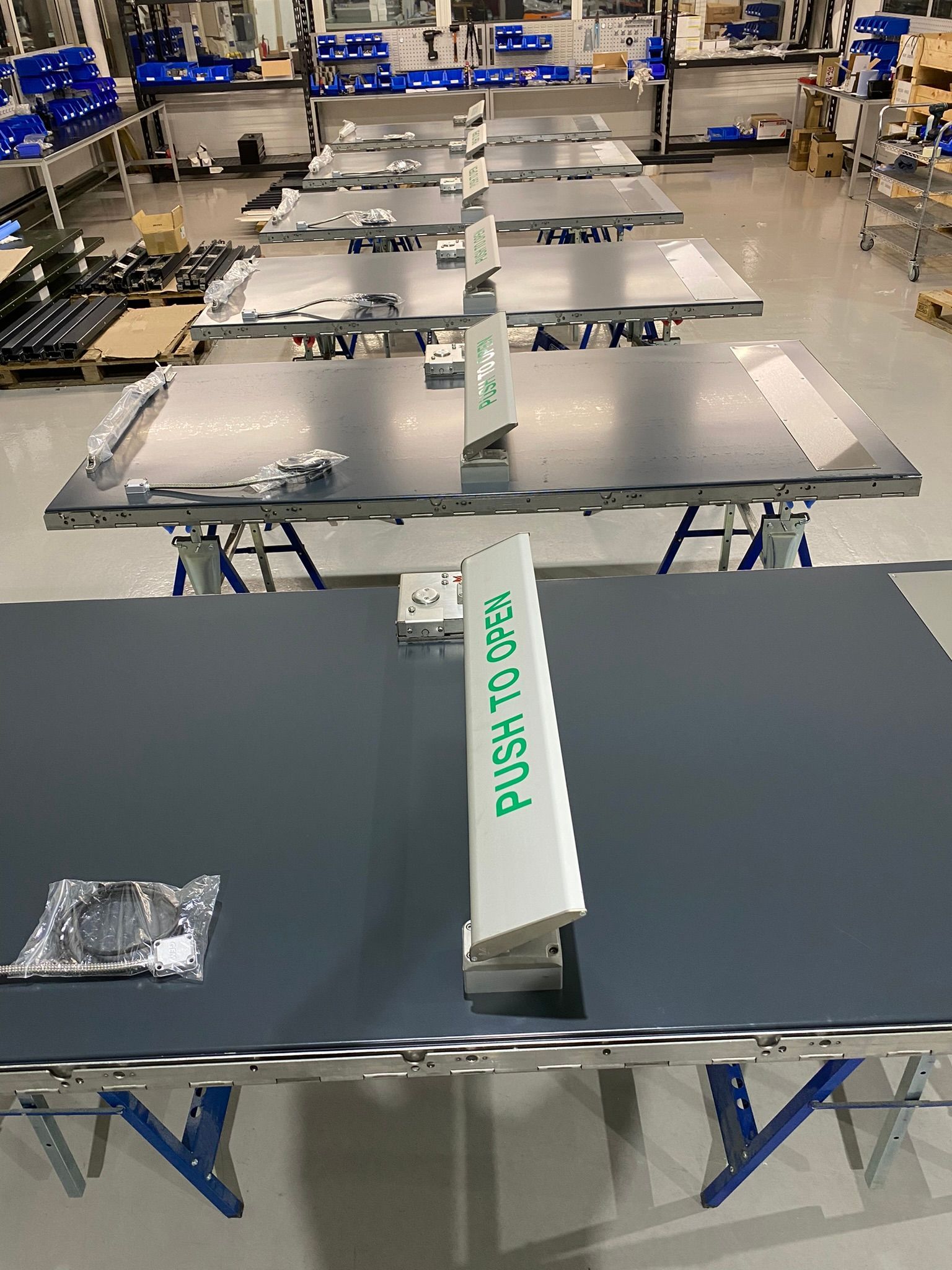 A row of tables in a factory with a sign that says `` push to open ''.