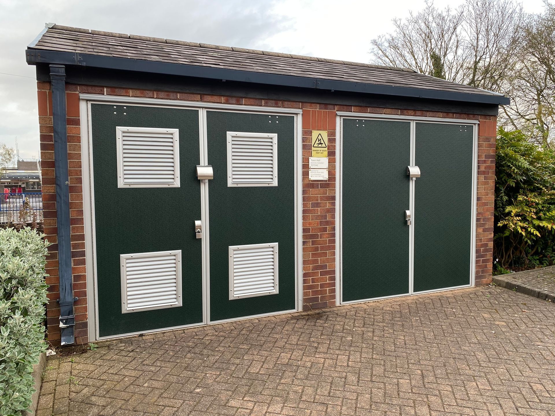 A brick building with green doors and a roof