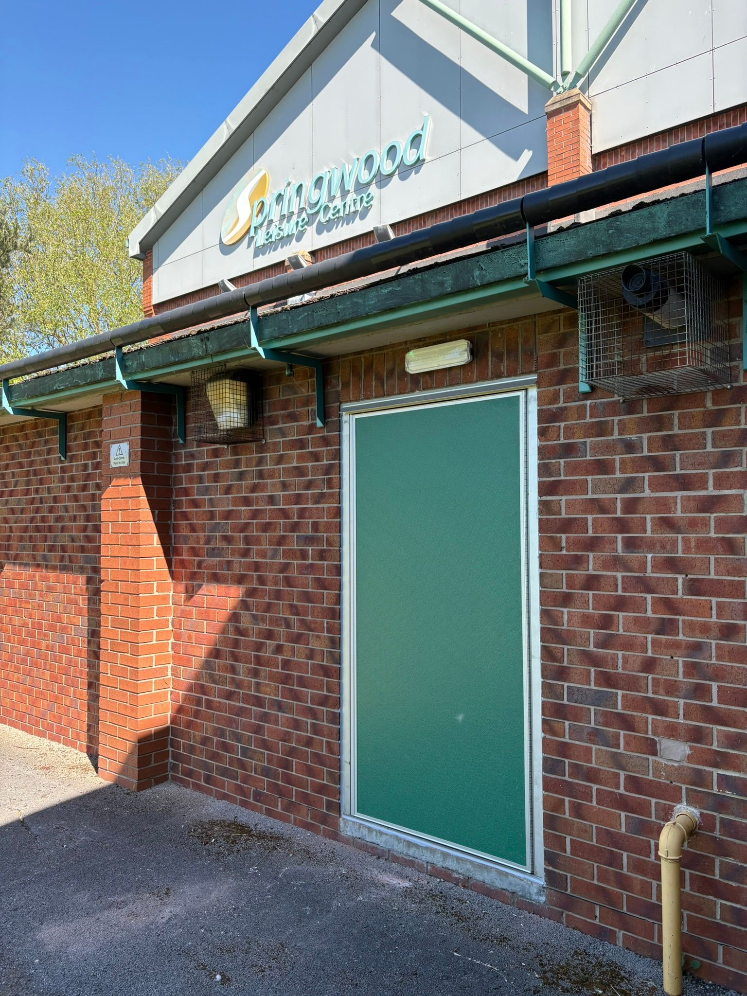 A brick building with green doors and a roof