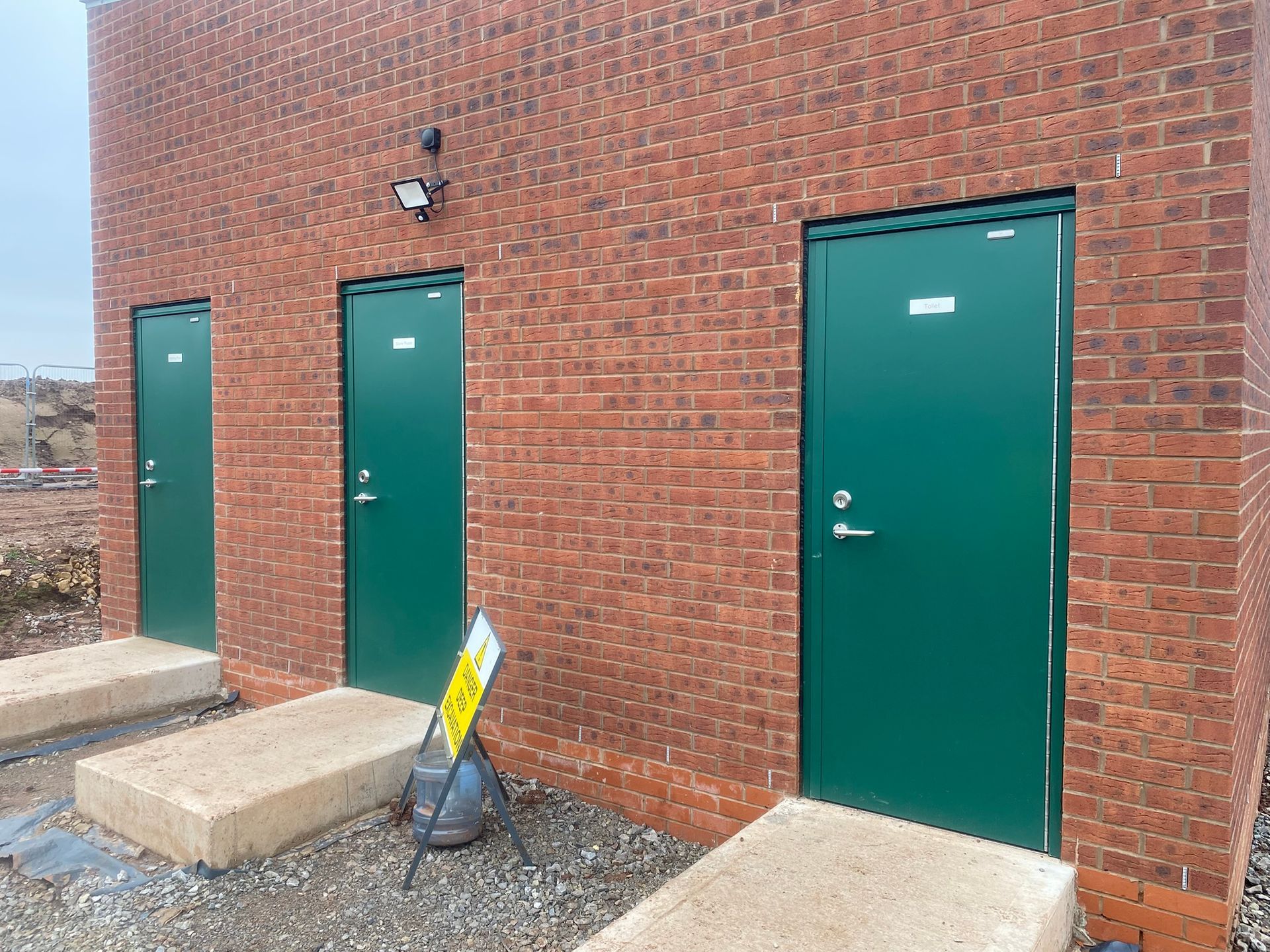A row of green doors on a brick building.