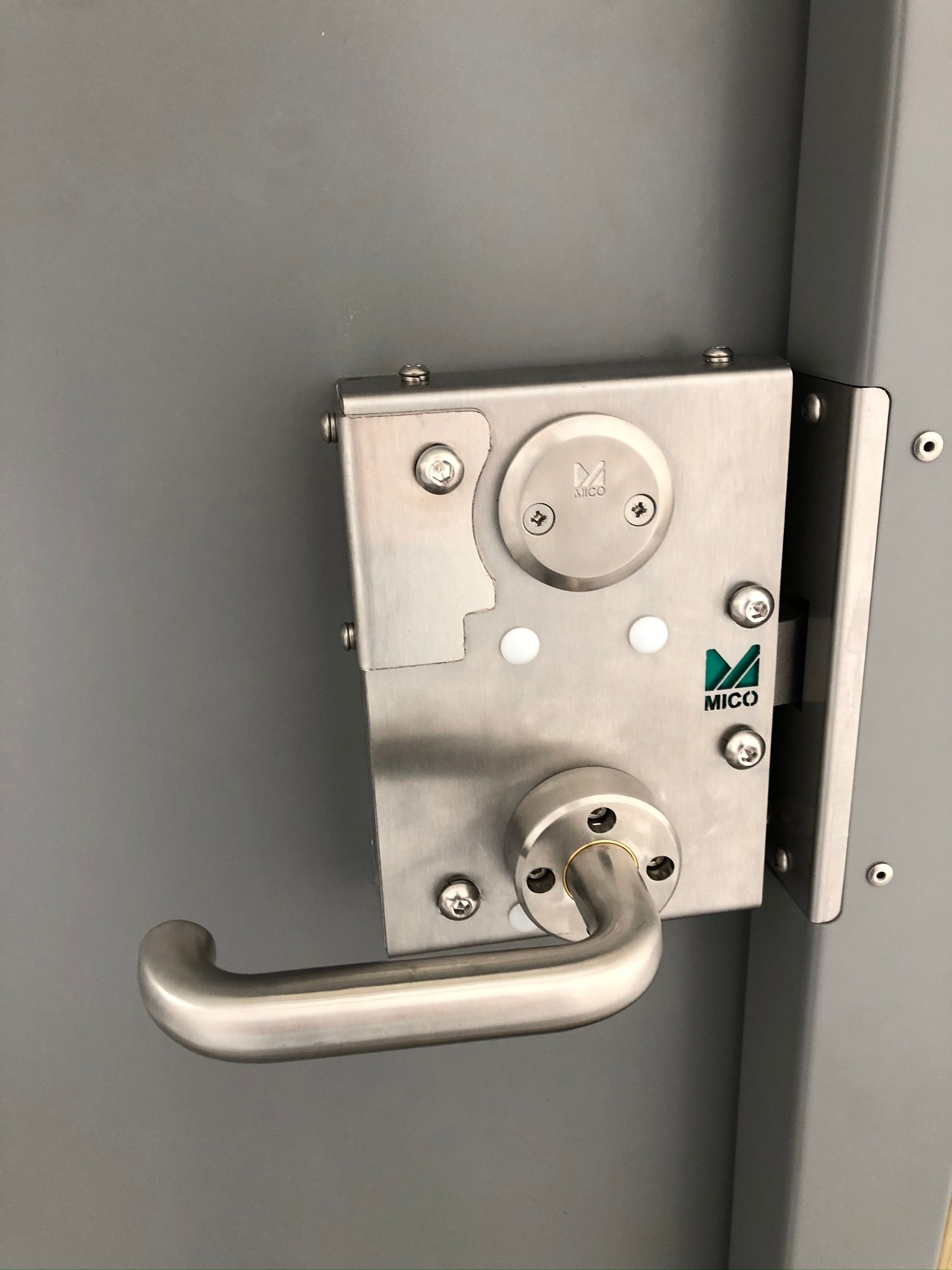 A close up of a stainless steel door lock with a handle.