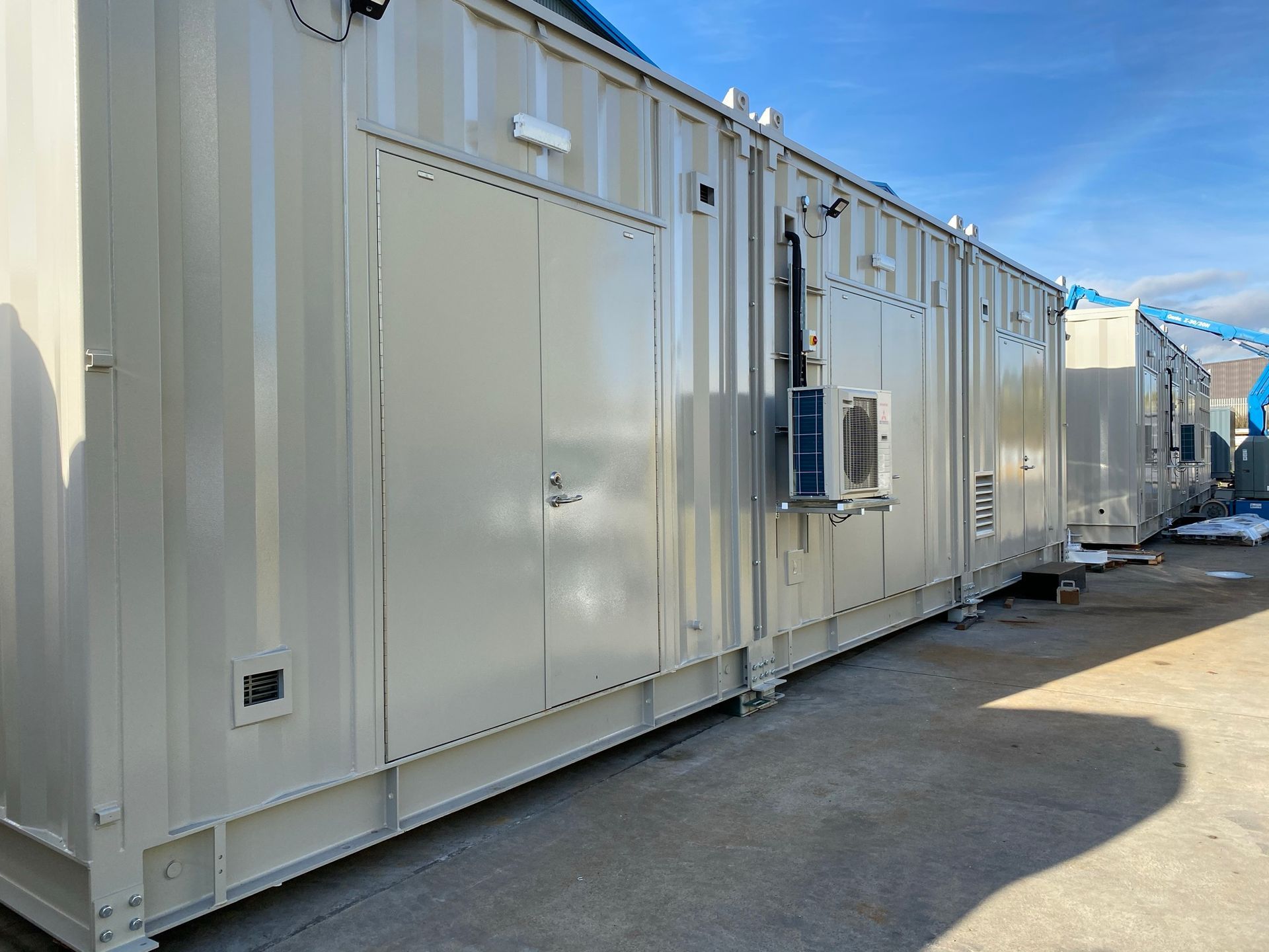 A large white building with a lot of windows and doors is sitting in a parking lot.