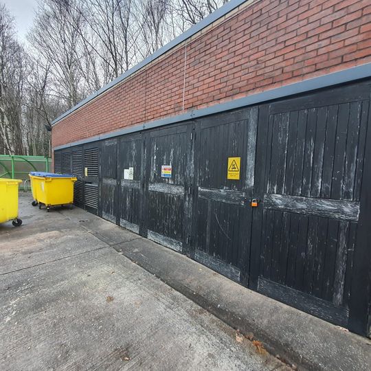 A brick building with green doors and a roof