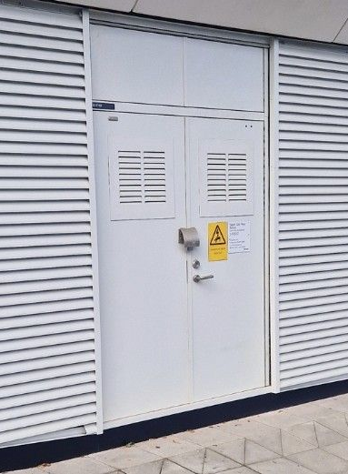 A large white building with a lot of windows and doors is sitting in a parking lot.