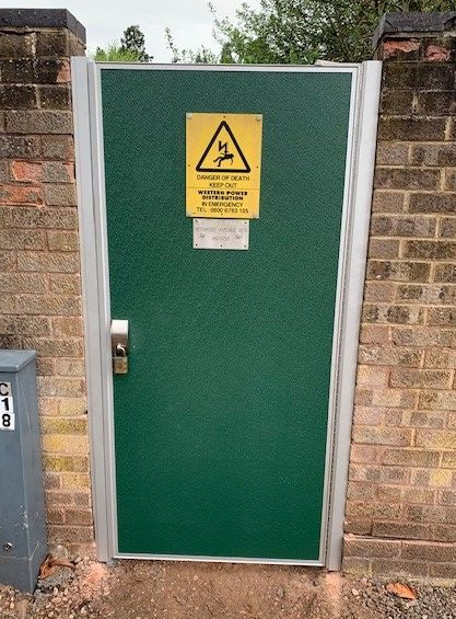 A green door with a yellow warning sign on it