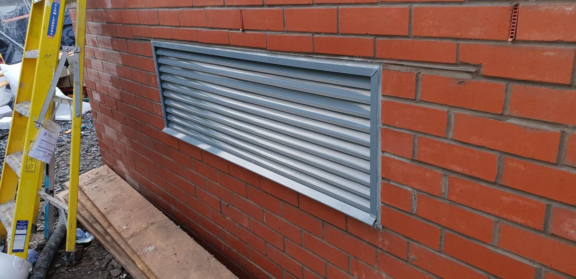 A brick wall with a metal grille on it.