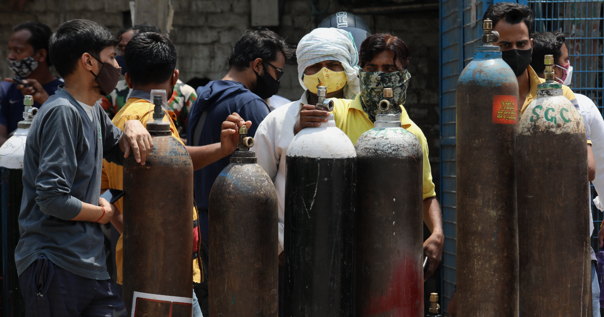 A group of people are standing around a row of gas cylinders.