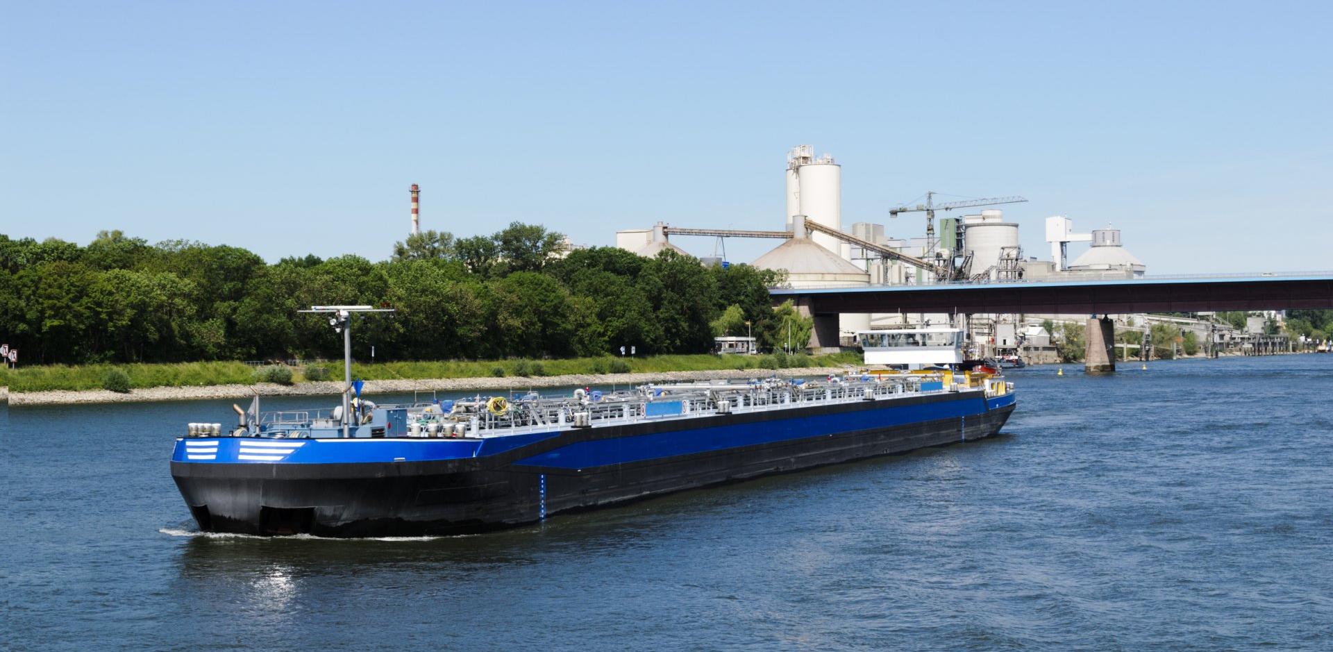 A large blue and black ship is floating on a river