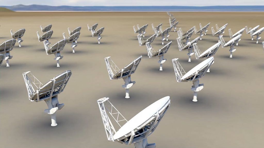 A group of satellite dishes are lined up in a field