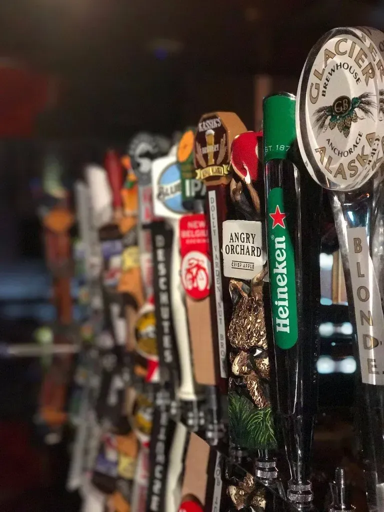 A row of beer taps with one that says heineken on it