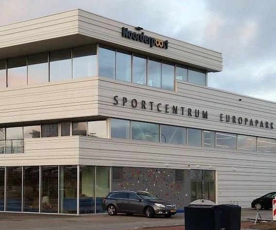 Het gebouw van Sportcentrum Europapark met grote ramen, tekst en geparkeerde auto's ervoor.