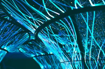 A man wearing a hard hat is carrying a bunch of blue wires.