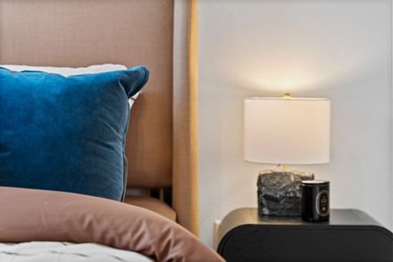 There is a candle and a cup of coffee on the nightstand next to the bed.