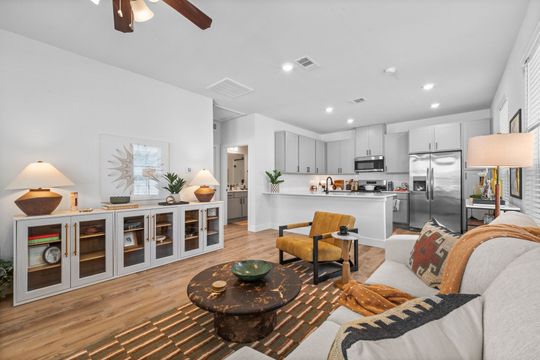 A living room with a couch , chair , coffee table and ceiling fan.