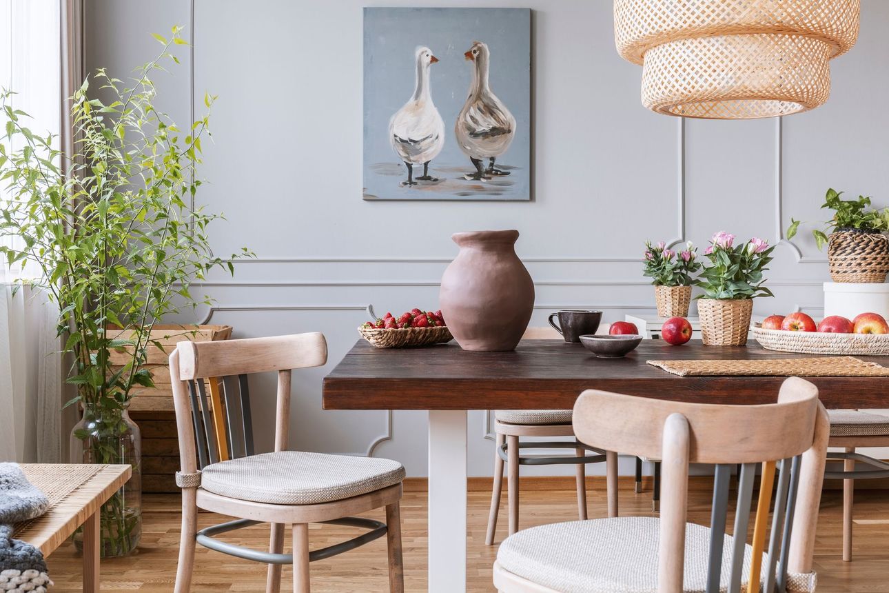 A dining room with a table and chairs and a painting of ducks on the wall.