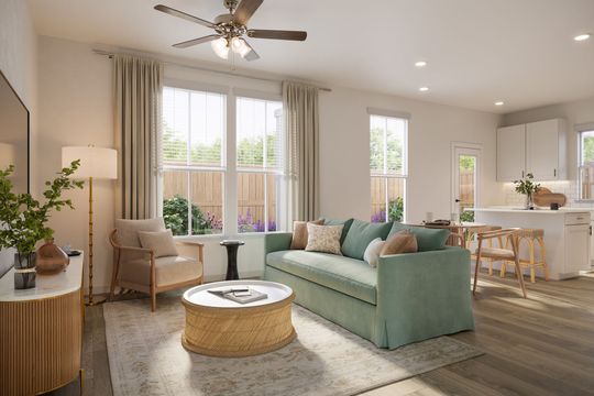 A living room with a couch , chair , coffee table and ceiling fan.